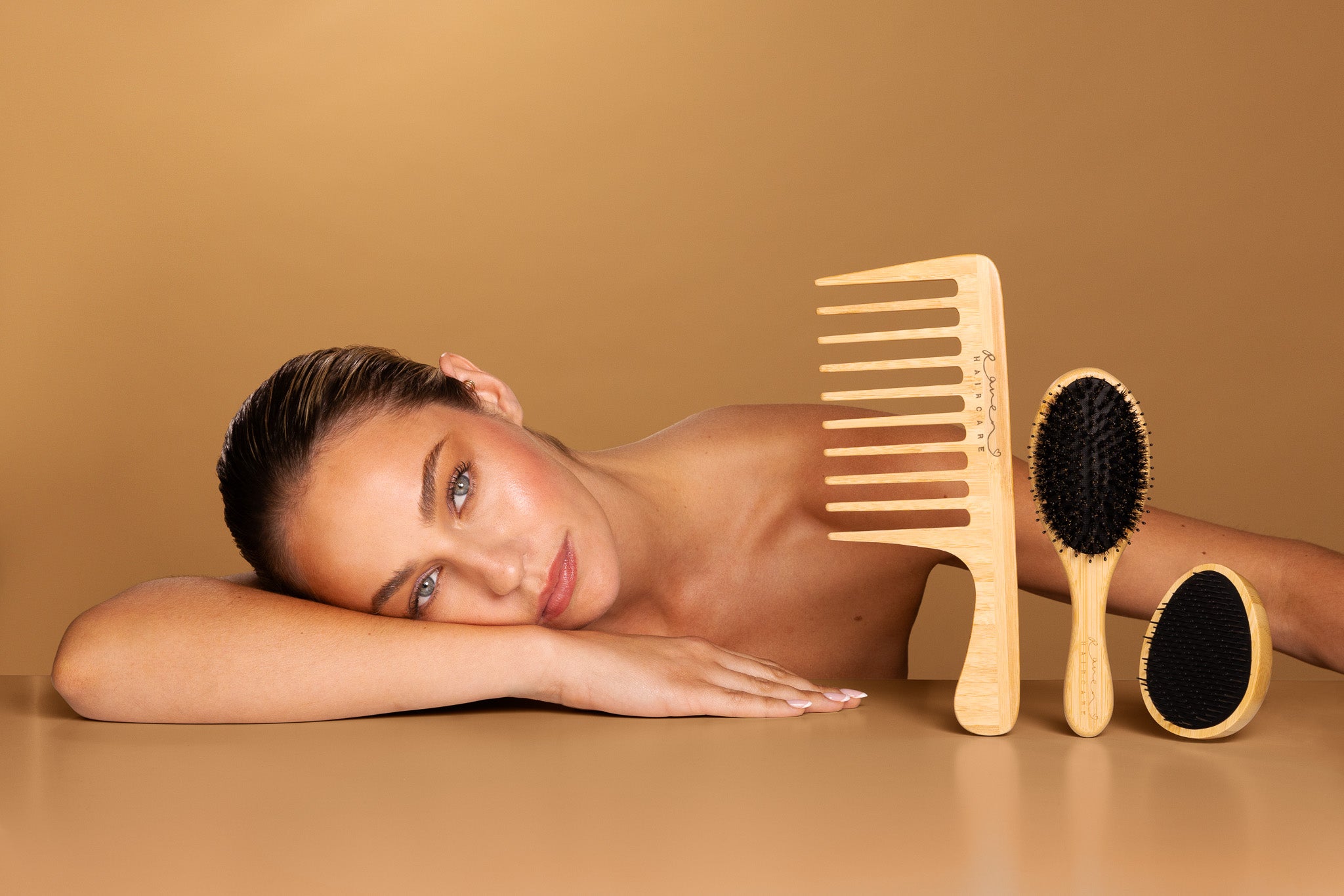 Modle lies across table with 3 hairbrushes 